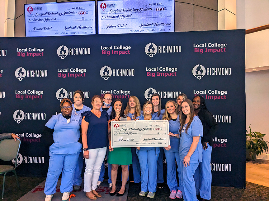 Surgical Tech students hold a big check