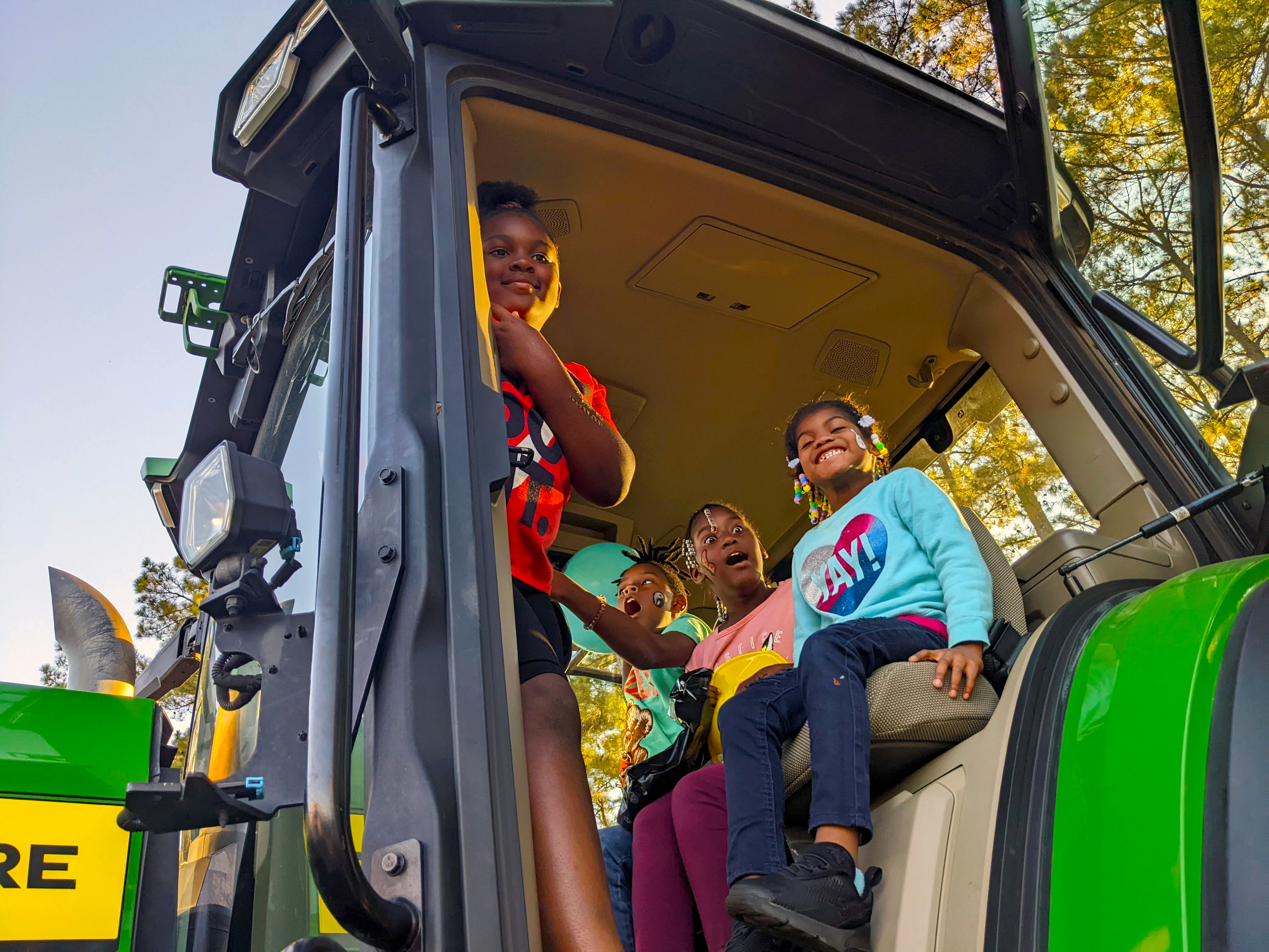 Kids sit in the seat of a big tractor